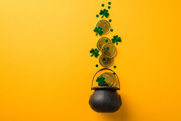 Top view photo of st patrick's day decorations shamrocks confetti and gold coins flying out of pot on isolated yellow background with copyspace