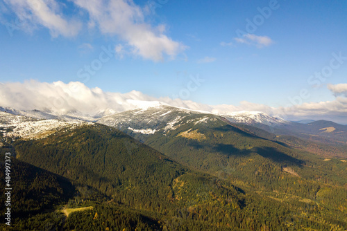 High mountain peaks covered with autumn spruce forest and high snowy summits © bilanol