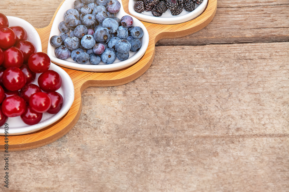 Portion wooden dish on light wooden background top view. Wooden partitioned dish divided into equal 3 section with berries.Compartmentals dish for food, dessert, fruit, berries and vegetable. Portion wooden dish on light wooden background top view. Wooden partitioned dish divided into equal 3 section with berries.Compartmentals dish for food, dessert, fruit, berries and vegetable.