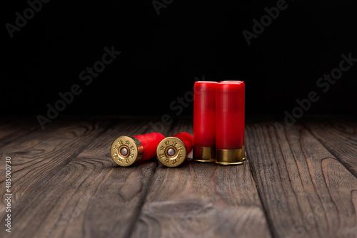 Shotgun cartridges on a brown wooden table. Ammunition for 12 gauge smoothbore weapons. photo