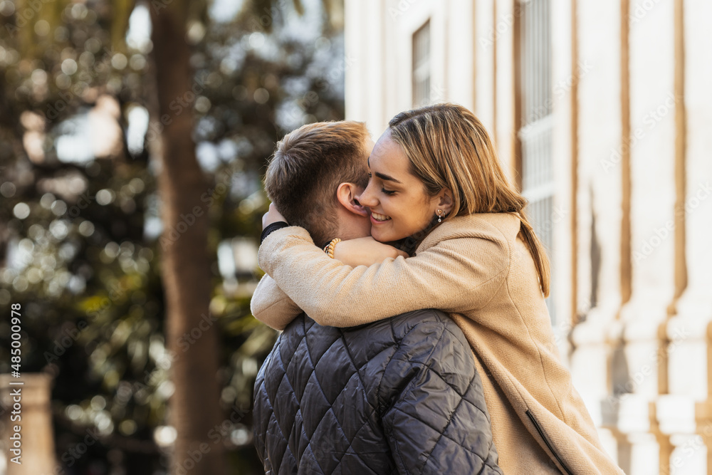 Fototapeta premium a smiling young woman hugs her boyfriend intensely