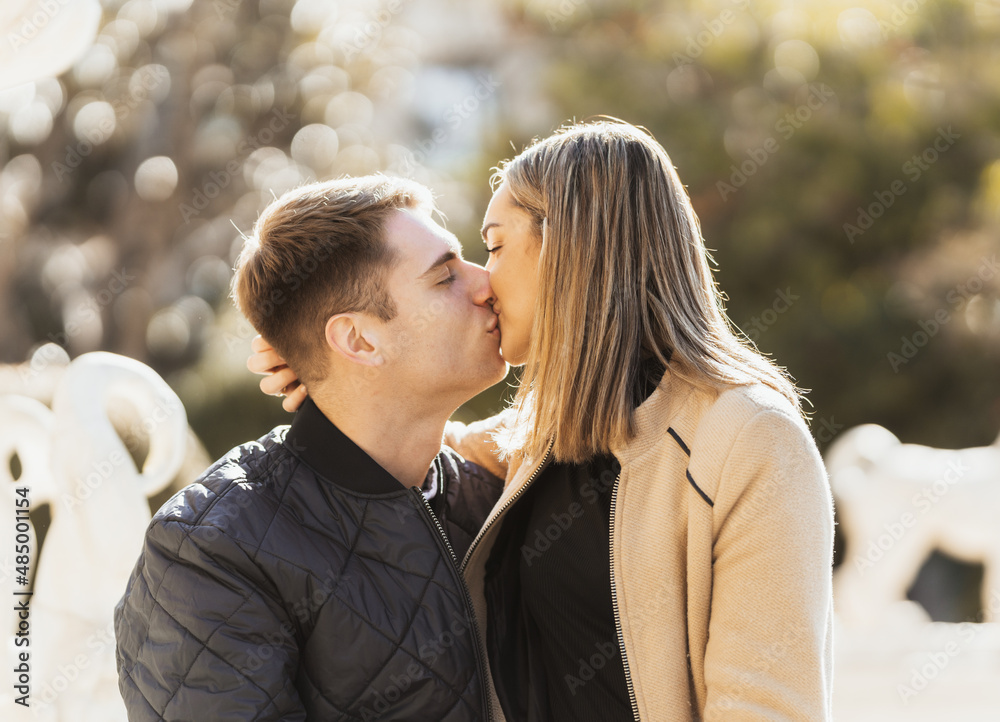 Fototapeta premium young woman kisses her boyfriend while sitting on his lap