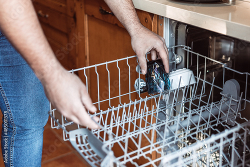 Obraz na plátne medium shot of a man's hands putting a dirty glass in the dishwasher