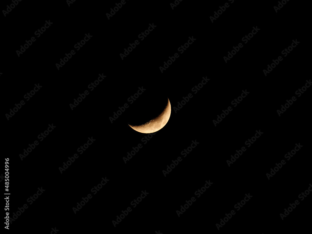 Yellow new moon isolated on dark blue sky, telephoto image. Yellow new moon isolated on dark blue sky, telephoto image.