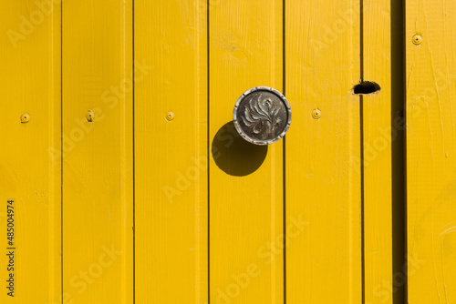 Yellow wooden door with a metal handle and a keyhole