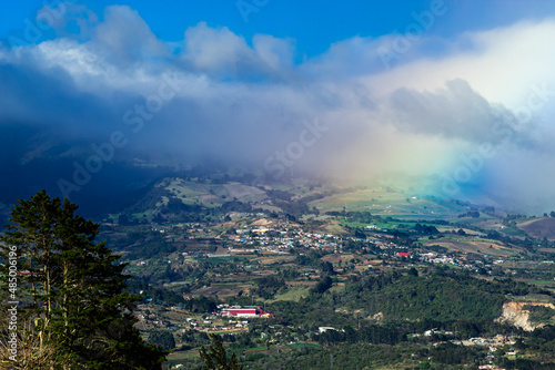 Landscape at Cartago, Costa Rica. A Cypress tree, a hill and the start of a rainbow.