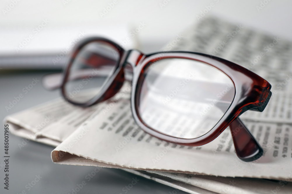 Newspapers and glasses on grey table, closeup Newspapers and glasses on grey table, closeup