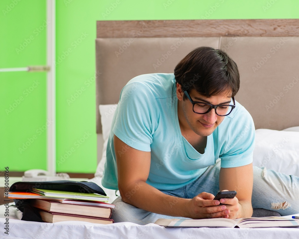 Student preparing for exams at home in bedroom sitting on the be Student preparing for exams at home in bedroom sitting on the be
