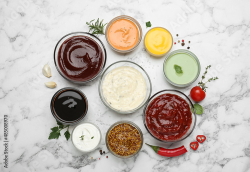 Many different sauces and herbs on white marble table