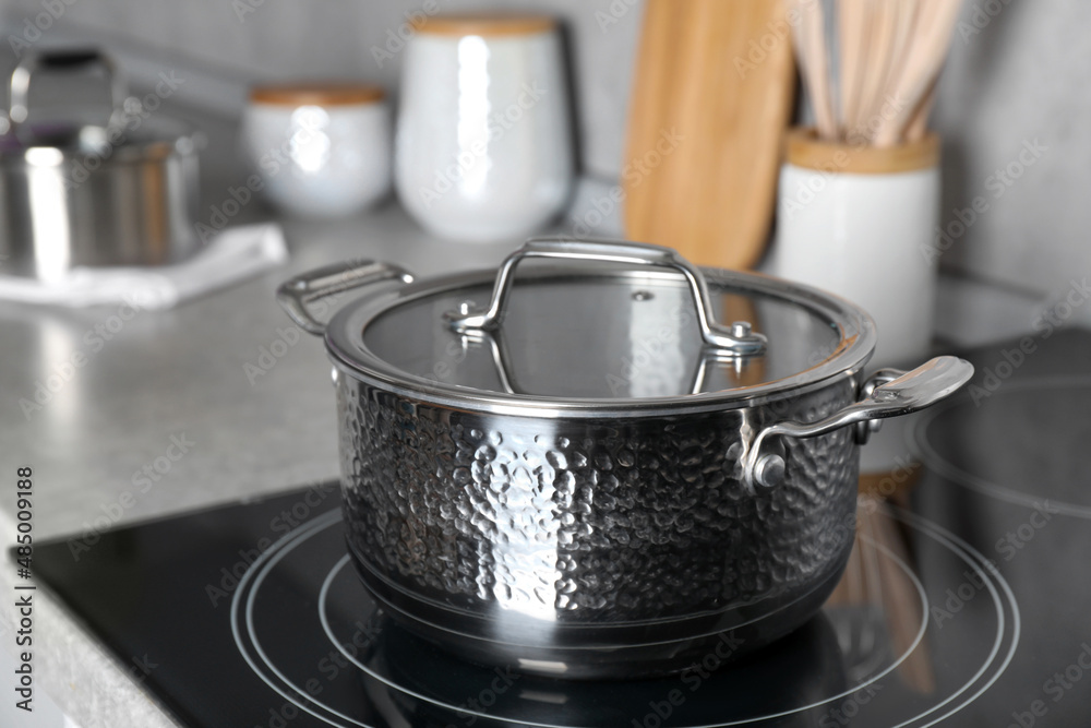 Pot with lid on cooktop in kitchen. Cooking utensil