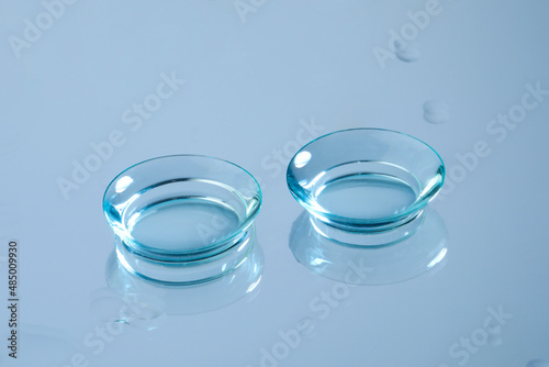 Pair of contact lenses on wet light blue reflective surface