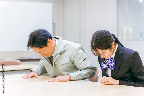 Photos 作業着を着た男性と事務スタッフの女性（謝罪）