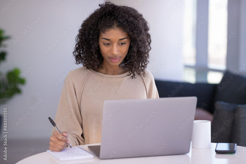 Young black woman at home remote working on laptop computer talking to her colleague Young black woman at home remote working on laptop computer talking to her colleague