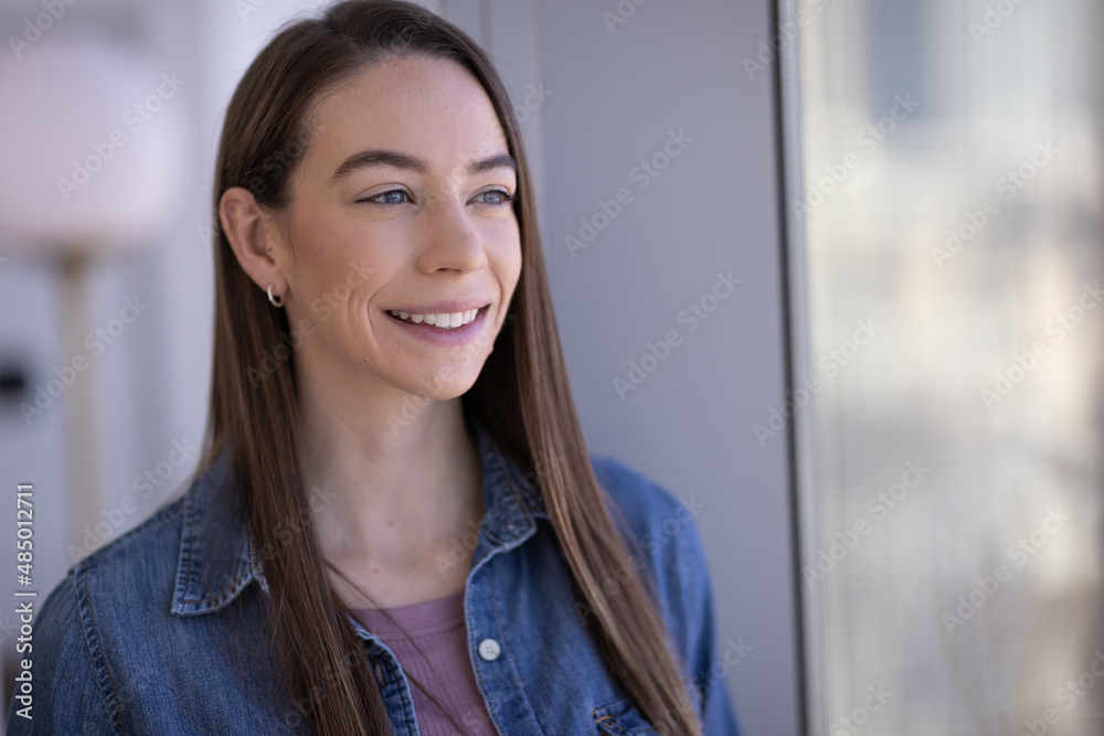 Caucasian woman smiling happy face portrait standing by a window Caucasian woman smiling happy face portrait standing by a window
