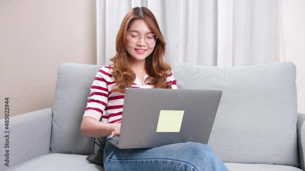 Young Asian women walk to sitting on the sofa and using laptops for business and social online. Young Asian women walk to sitting on the sofa and using laptops for business and social online.