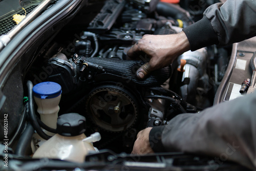 Close up hands of auto mechanic doing car service and maintenance. Services car engine machine. © Dusan