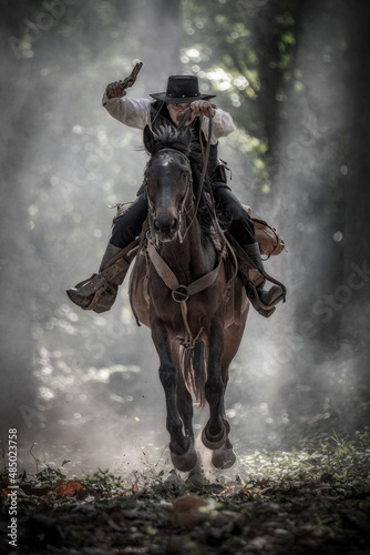 Cowboy is riding a horse and holding a long gun in his hand, ready for shooting. Cowboy concept.