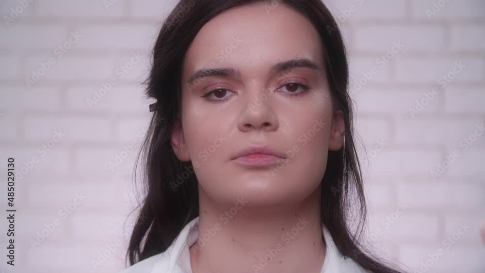 Young caucasian fashion model preparing for a photo shoot under professional soft lighting. Make-up artist applies face foundation on a woman. High quality 4k footage Young caucasian fashion model preparing for a photo shoot under professional soft lighting. Make-up artist applies face foundation on a woman. High quality 4k footage