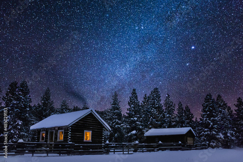 A beautiful snowy cabin in the winter mountains of Montana with stars at night