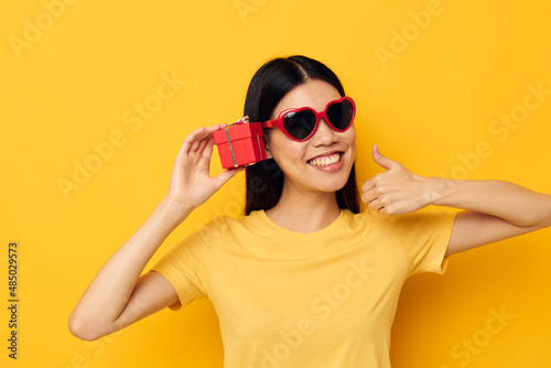 Charming young Asian woman wearing sunglasses small gift box studio model unaltered