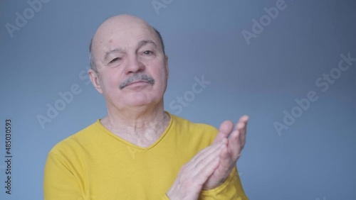Senior man clapping and applauding with disbelief at his face. Studio shot