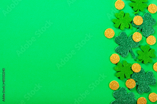 Handmade clover leaves and coins on green fabric flat lay background
