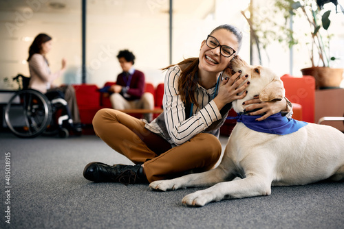 Happy businesswoman embraces her Labrador therapy dog and having fun in office. photo