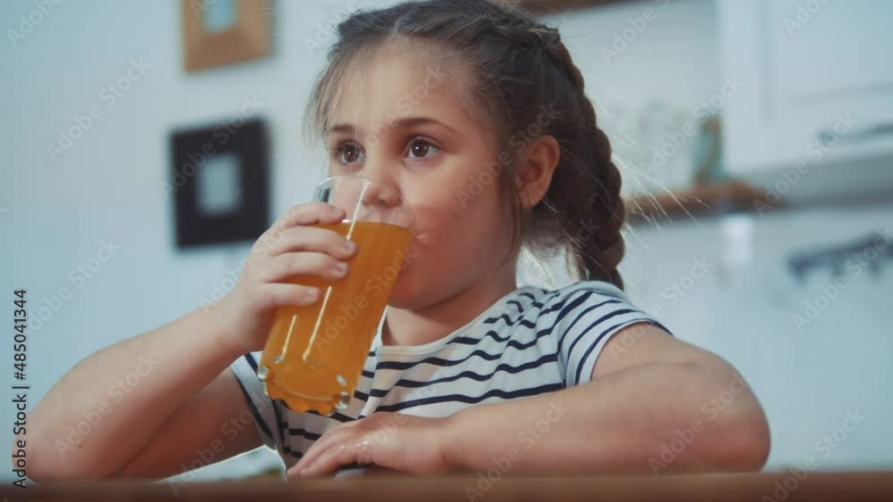little girl child drinking juice. healthy eating a child eating breakfast kid dream concept. daughter girl in kitchen drinks juice and licks her lips. positive kid orange smiling having breakfast