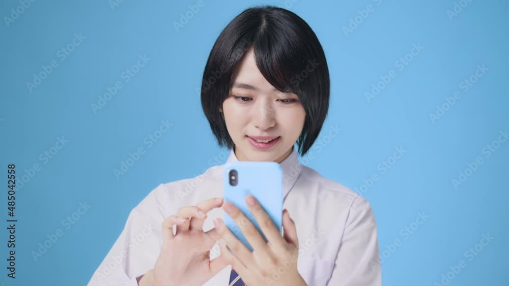 スマホを見て笑顔になる女性 女子高生 スマホを見て笑顔になる女性 女子高生