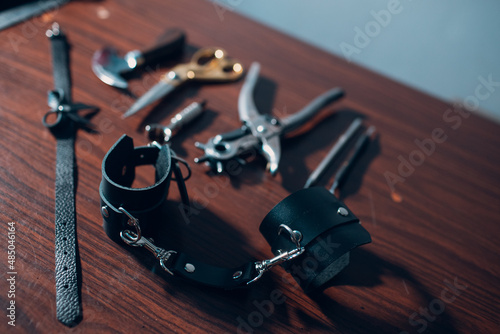 Tanner tools and leather handcuffs on table. photo