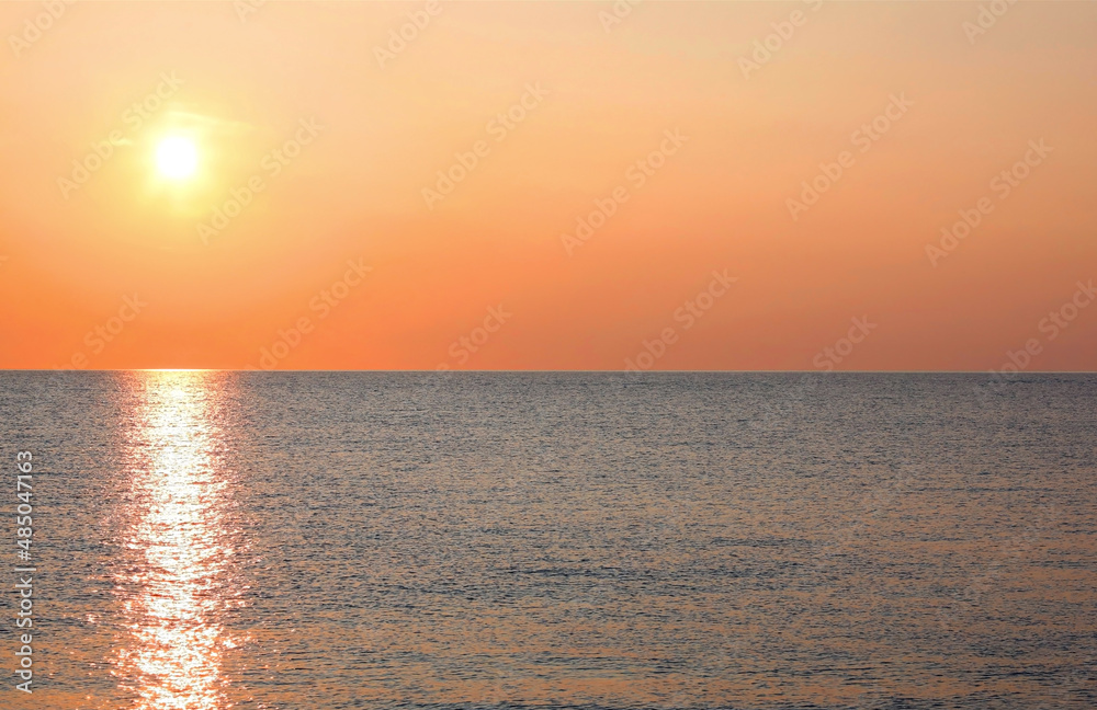 fiery sun over the calm sea with no boat and no people ideal as a backdrop of tranquility