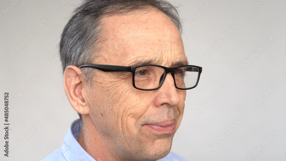 An elderly man squints, puts on his glasses An elderly man squints, puts on his glasses