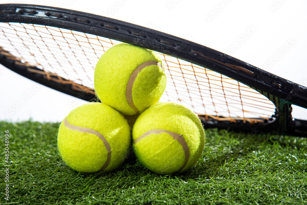 tennis balls wit racket on artificial grass court