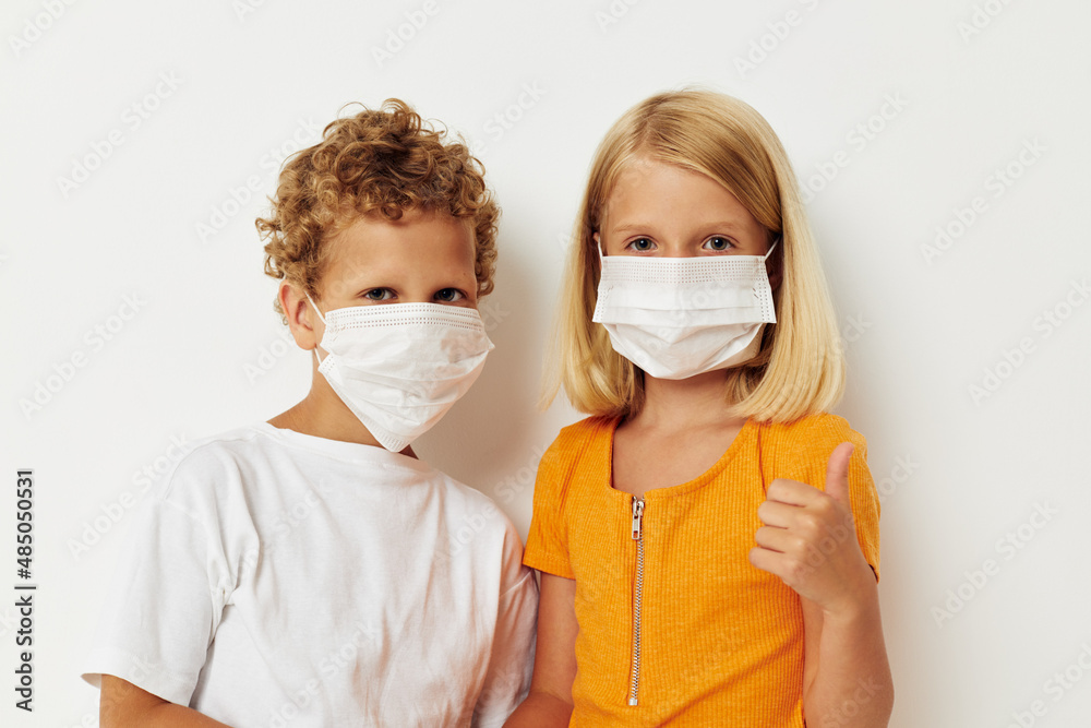 Portrait of cute children fun medical mask stand side by side close-up lifestyle unaltered