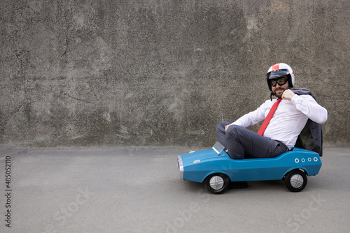 Funny businessman driving retro pedal car outdoor