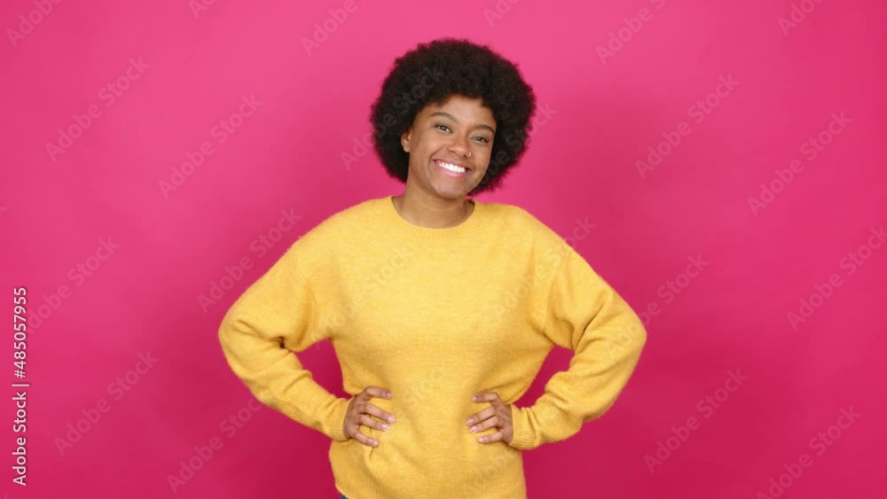 Young African American woman posing with arms at hip and laughing over isolated background