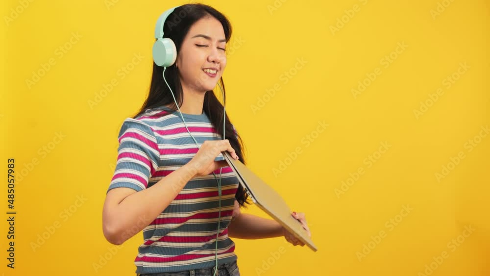 Happy attractive asian young woman dancing isolated on yellow background.Cheerful pretty girl happy with tablet notebook online music smiling and moving body follow music with positive. Happy attractive asian young woman dancing isolated on yellow background.Cheerful pretty girl happy with tablet notebook online music smiling and moving body follow music with positive.