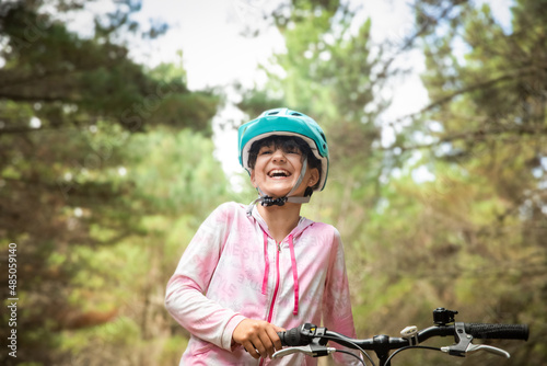 happy child girl riding a bike on natural background, forest or park. healthy lifestyle, family day out