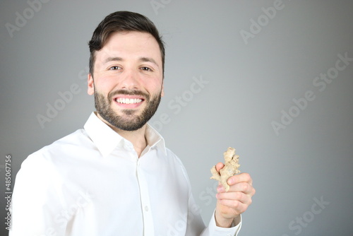 Happy caucasian man wearing white shirt is showing ginger root photo