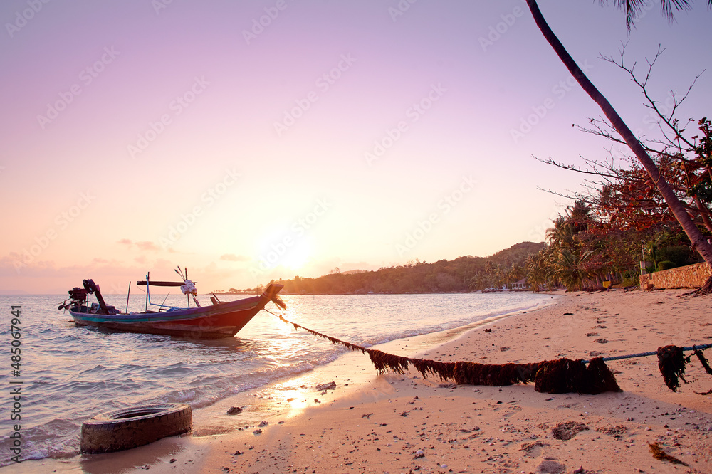 Beautiful sunset on the sea beach with traditional thai longtail boat.