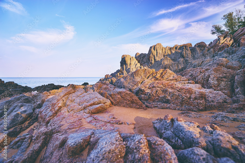 Obraz premium Beautiful beach with golden sand, rocks and blue sky.