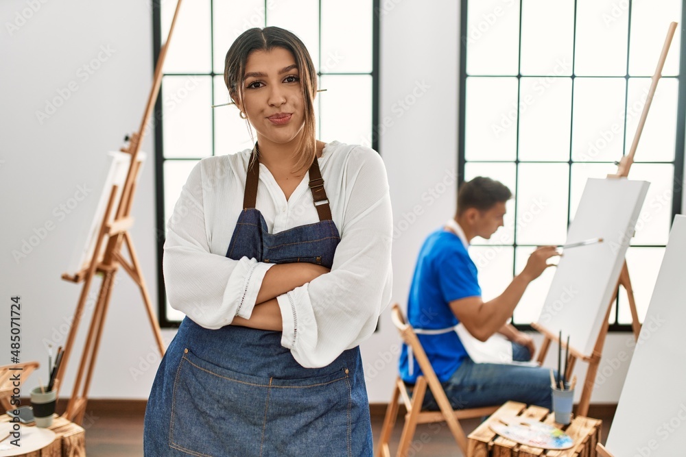 Young hispanic couple at art studio happy face smiling with crossed arms looking at the camera. positive person.