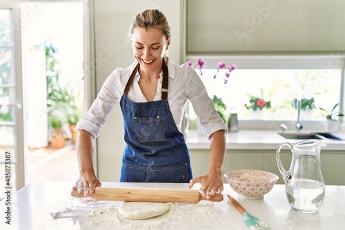 Fotografi Young blonde woman smiling confident kneading pizza dough at kitchen
