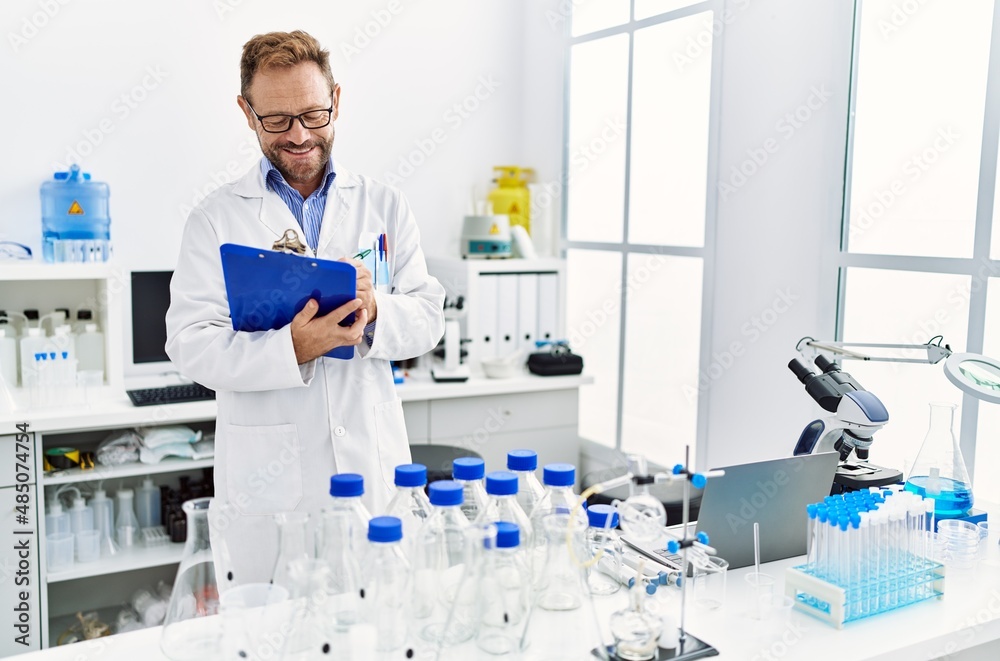 Middle age hispanic man smiling confident wearing scientist uniform at laboratory Middle age hispanic man smiling confident wearing scientist uniform at laboratory
