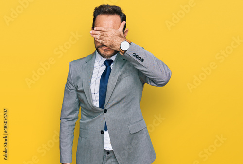 Fotografía Middle age man wearing business clothes covering eyes with hand, looking serious and sad