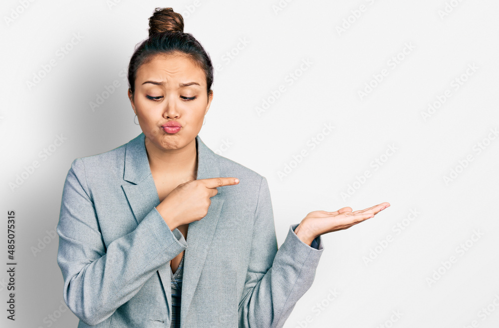 Young hispanic girl pointing open palm with finger making fish face with mouth and squinting eyes, crazy and comical. Young hispanic girl pointing open palm with finger making fish face with mouth and squinting eyes, crazy and comical.