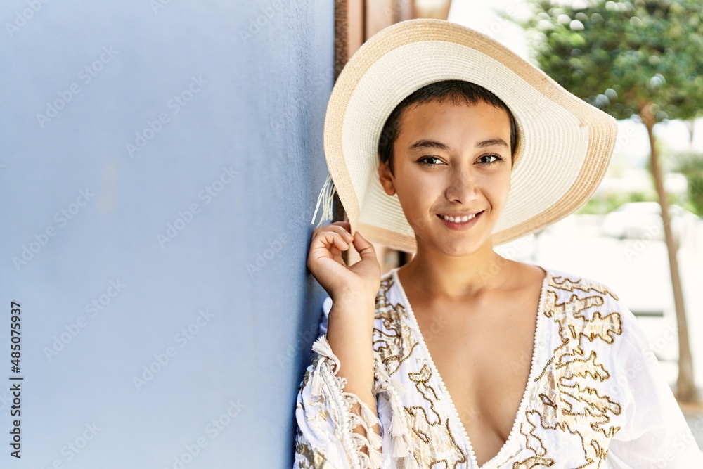 Young hispanic woman smiling confident wearing summer hat at street