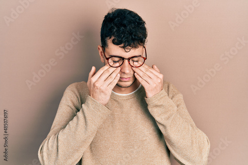 Young hispanic man wearing casual clothes and glasses rubbing eyes for fatigue and headache, sleepy and tired expression. vision problem