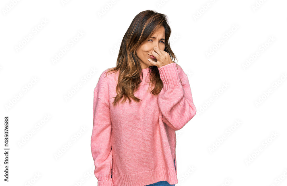 Young hispanic woman wearing casual clothes smelling something stinky and disgusting, intolerable smell, holding breath with fingers on nose. bad smell Young hispanic woman wearing casual clothes smelling something stinky and disgusting, intolerable smell, holding breath with fingers on nose. bad smell