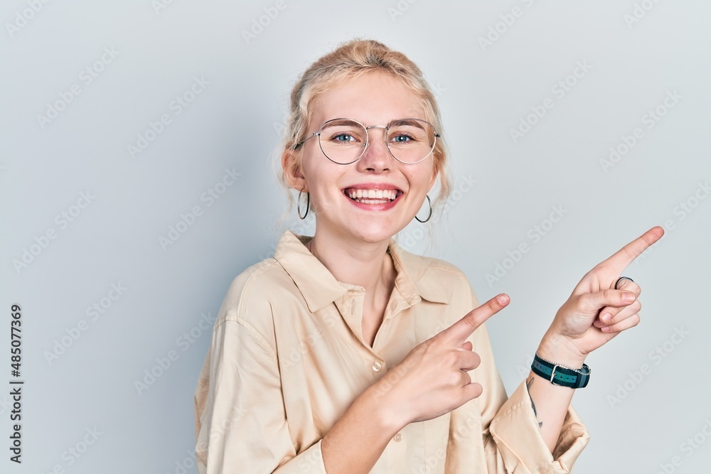 Beautiful caucasian woman with blond hair wearing casual look and glasses smiling and looking at the camera pointing with two hands and fingers to the side. Beautiful caucasian woman with blond hair wearing casual look and glasses smiling and looking at the camera pointing with two hands and fingers to the side.